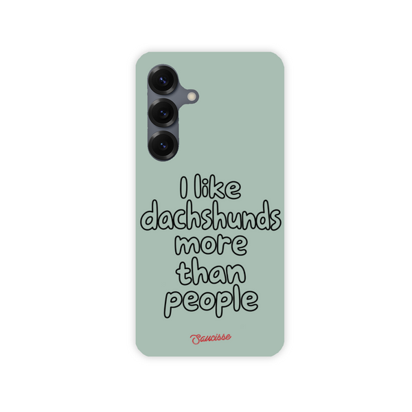 Saucisse sage-green phone case for Galaxy S25, with “I like dachshunds more than people” lettering and a red signature.