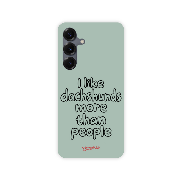 Saucisse sage-green phone case for Galaxy S25 Plus, with “I like dachshunds more than people” lettering and a red signature.
