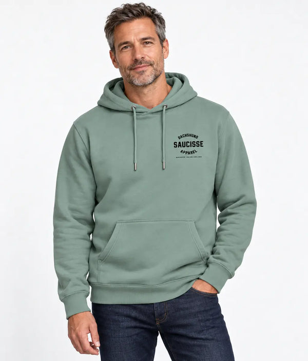 Man wearing the Saucisse Manchester England unisex hoodie in Jade Green, showing the small black Dachshund Apparel chest print.