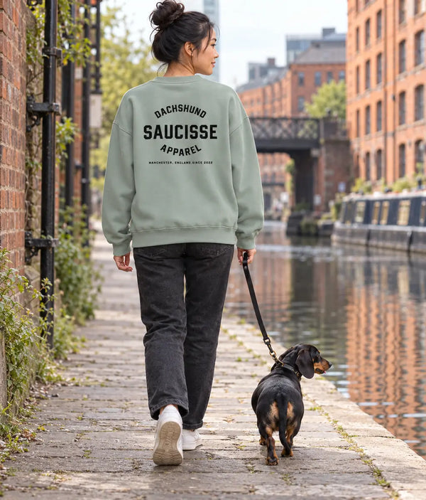 Back of the Jade Green Saucisse Manchester England unisex sweater worn on a canal walk with a dachshund