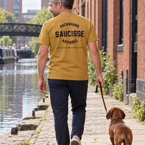 Rear lifestyle view of a man wearing the Saucisse Dachshund Apparel Manchester England T-shirt in Ochre