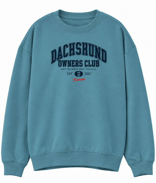 Front of the Saucisse Dachshund Owners Club 2026 unisex sweater in Adriatic Blue, with a navy varsity design and red Saucisse signature