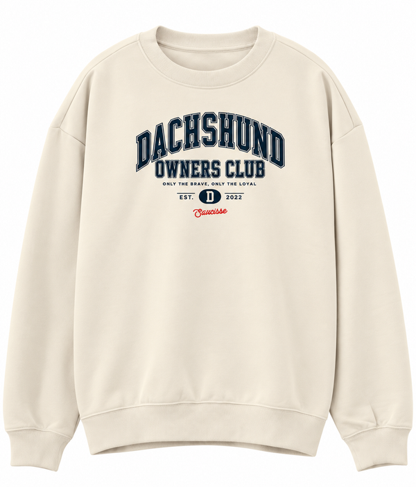 Front of the Saucisse Dachshund Owners Club 2026 unisex sweater in Ivory, with a navy varsity design and red Saucisse signature