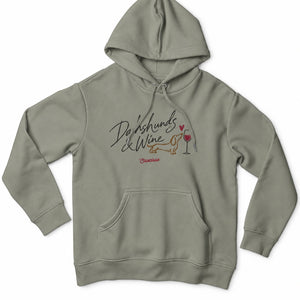 Front view of the Almond Green Saucisse Dachshunds & Wine women's hoodie, with matching drawcords and a centred dachshund and wine print.