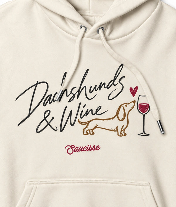 Close-up of the Dachshunds & Wine chest print on the Ivory hoodie, showing cotton texture and matching Ivory drawcords.