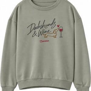 Front view of the Saucisse Dachshunds & Wine sweater in Almond Green, showing the chest artwork.
