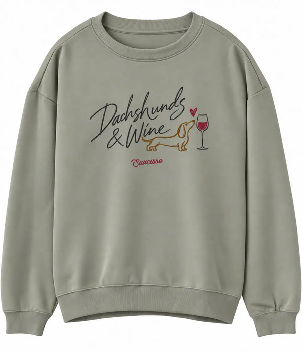 Front view of the Saucisse Dachshunds & Wine sweater in Almond Green, showing the chest artwork.