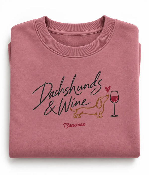 Folded Antique Rose Saucisse sweater with the Dachshunds & Wine chest print visible.