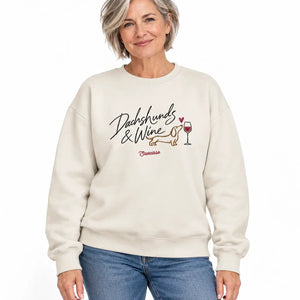 Woman with short grey hair wearing the Saucisse Dachshunds & Wine sweater in Ivory, styled with jeans in a white studio.