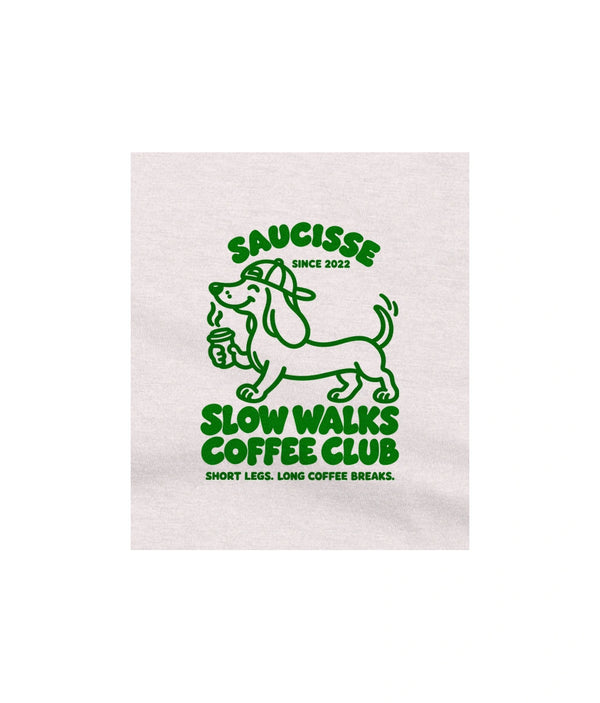 Close-up of the green Slow Walks Coffee Club chest print on the Vintage White Saucisse T-shirt, showing the fabric texture
