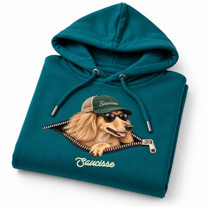 Folded Saucisse Unzipped long-haired unisex hoodie in Peacock Green, showing the long-haired dachshund and printed zip artwork.