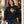Woman wearing the Saucisse Unzipped long-haired unisex sweater in Black outside a cafe.