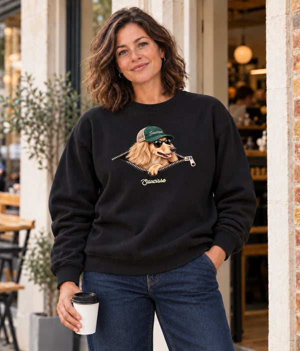 Woman wearing the Saucisse Unzipped long-haired unisex sweater in Black outside a cafe.
