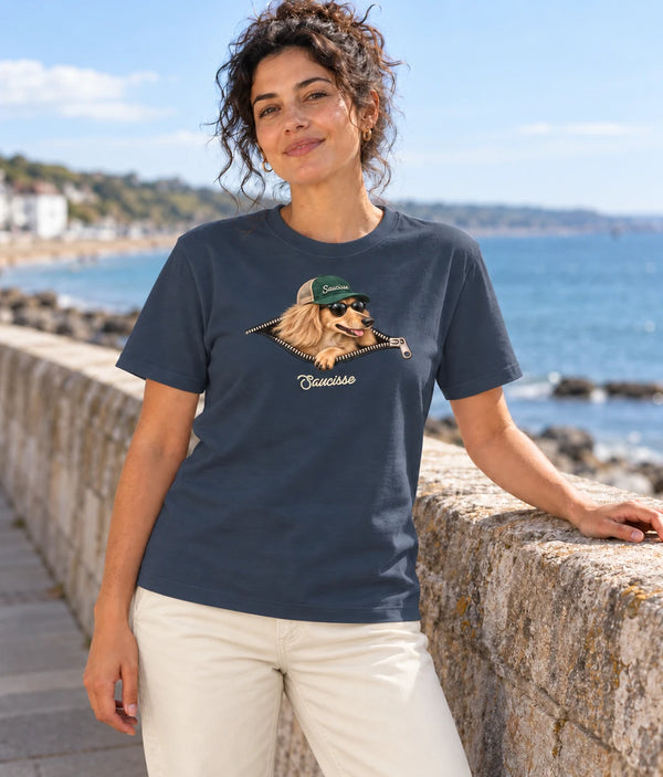 Woman wearing the Saucisse Unzipped long-haired unisex T-shirt in India Ink Grey beside the coast.