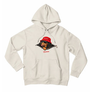 Front view of the Ivory Saucisse Unzipped Short Haired unisex hoodie, with a dachshund in a red Saucisse bucket hat and sunglasses peeping through an illustrated zip and a red Saucisse signature.