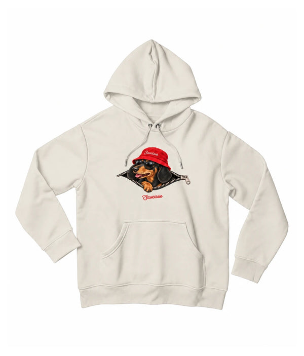 Front view of the Ivory Saucisse Unzipped Short Haired unisex hoodie, with a dachshund in a red Saucisse bucket hat and sunglasses peeping through an illustrated zip and a red Saucisse signature.