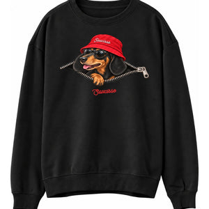 Front view of the Black Saucisse Unzipped Short Haired unisex sweater, with a dachshund in a red Saucisse bucket hat and sunglasses peeping through an illustrated zip and a red Saucisse signature.