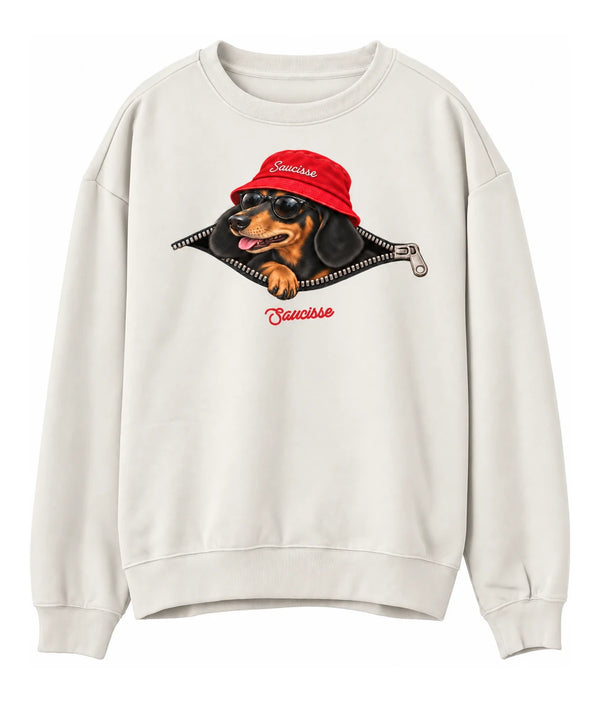 Front view of the Ivory Saucisse Unzipped Short Haired unisex sweater, with a dachshund in a red Saucisse bucket hat and sunglasses peeping through an illustrated zip and a red Saucisse signature.