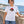 Woman wearing the White Saucisse Unzipped Short Haired unisex T-shirt beside the sea, with the dachshund front print visible.