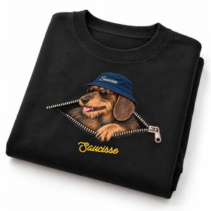 Folded Saucisse Unzipped wire-haired unisex sweater in Black, showing the dachshund, navy bucket hat and printed zip artwork.