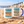 White and blue Southwold Sausage Dog Walk 2026 mugs on a sandy British beach with beach huts