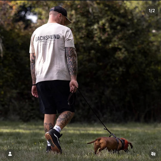 A customer in a Dachshund Owners Training Club T-shirt walking a dachshund
